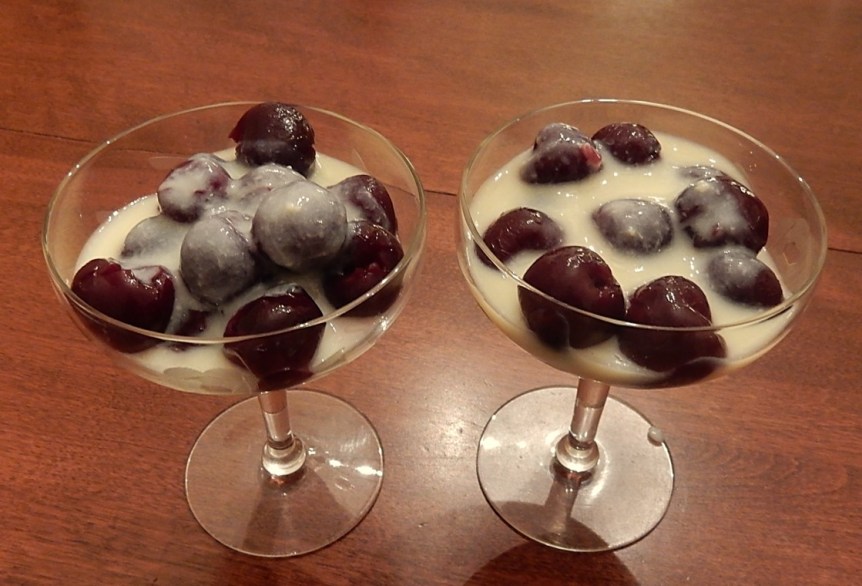Cherries in custard sauce in stemmed glasses