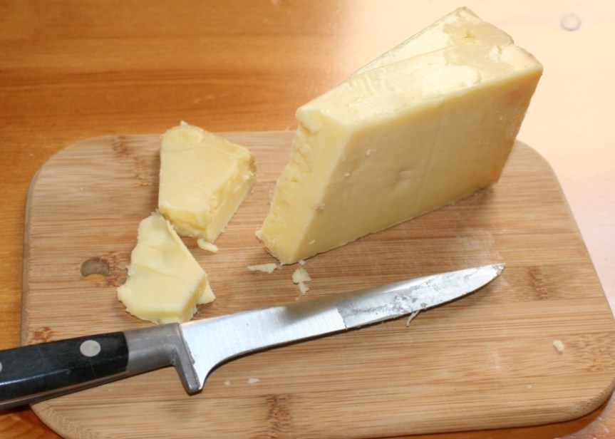 Cheddar Cheese and Knife on Cutting Board